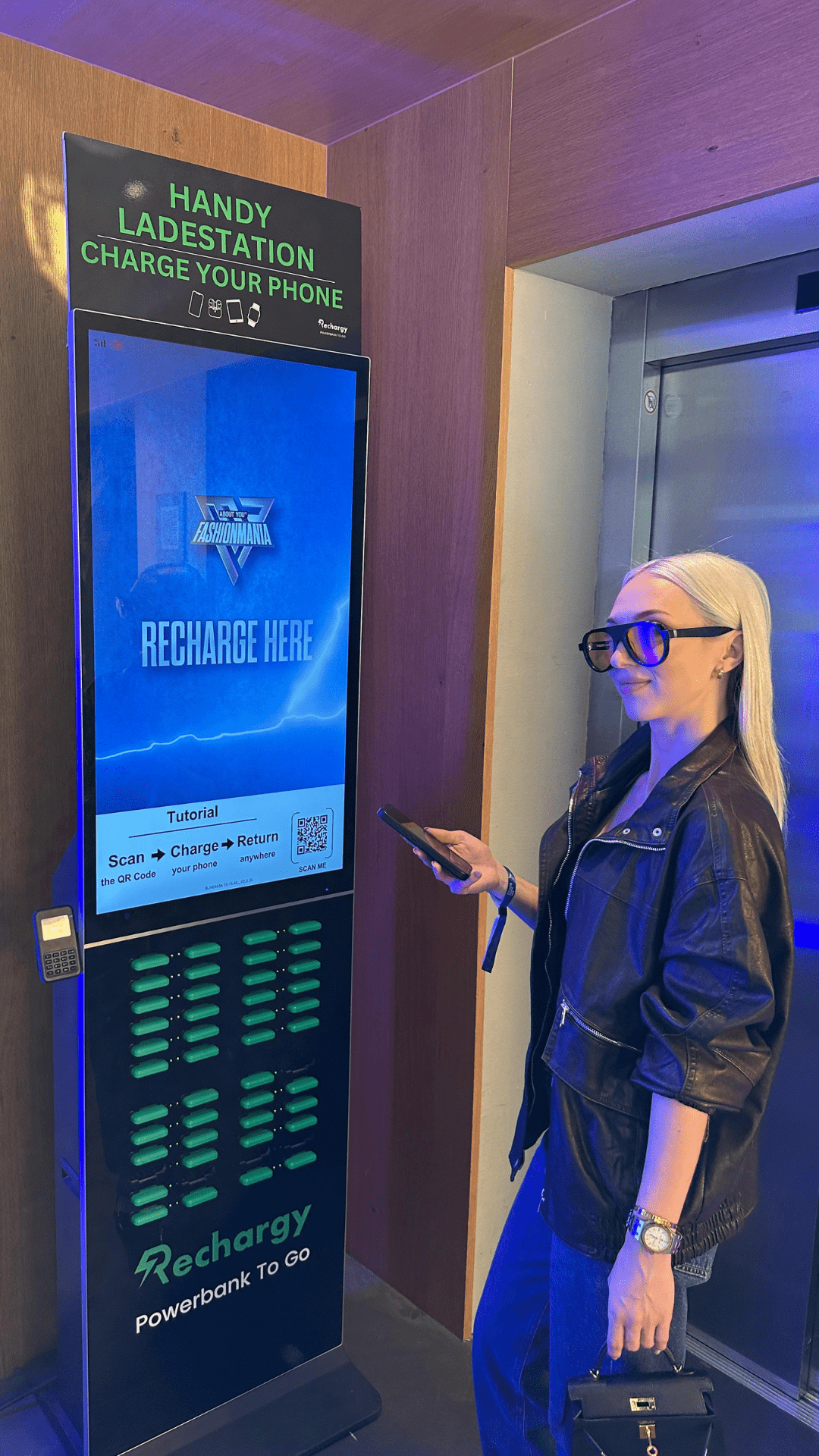 Besucherin an einer Rechargy Powerbank-Station mit Werbescreen in der Uber Arena Berlin
