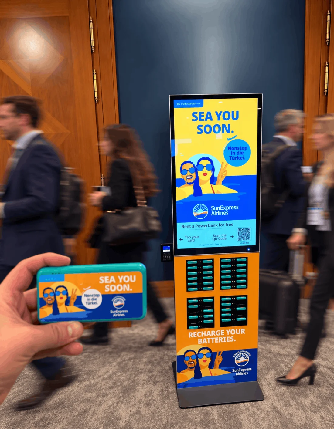 SunExpress Powerbank-Station mit Besuchern auf einer Messe